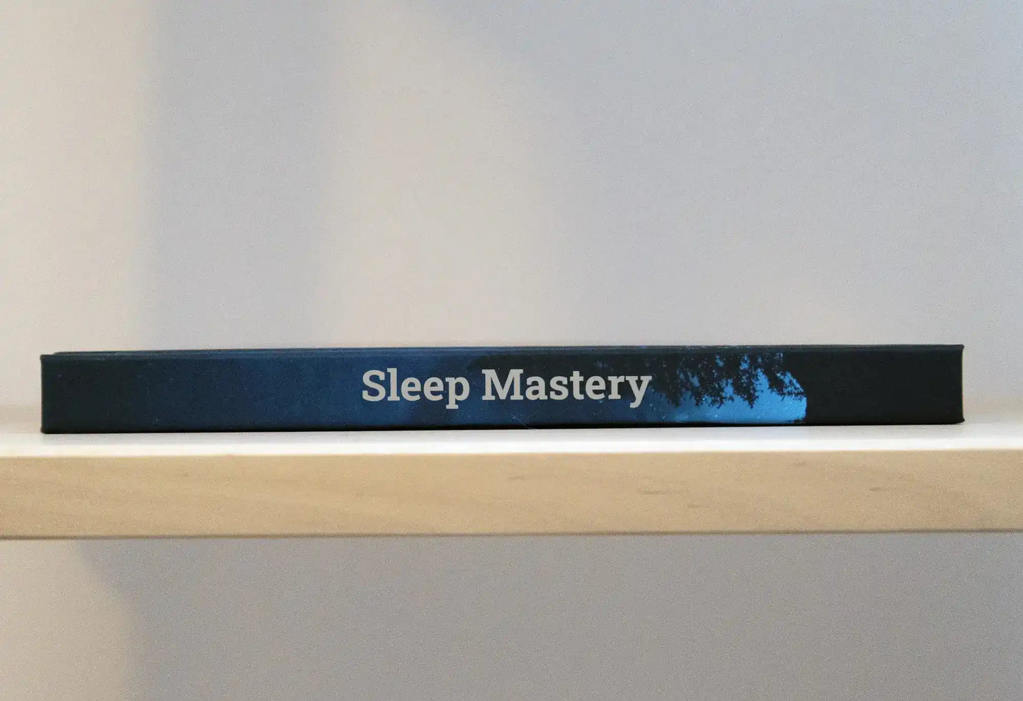 Sleep Mastery Journal lying flat on a bookshelf.