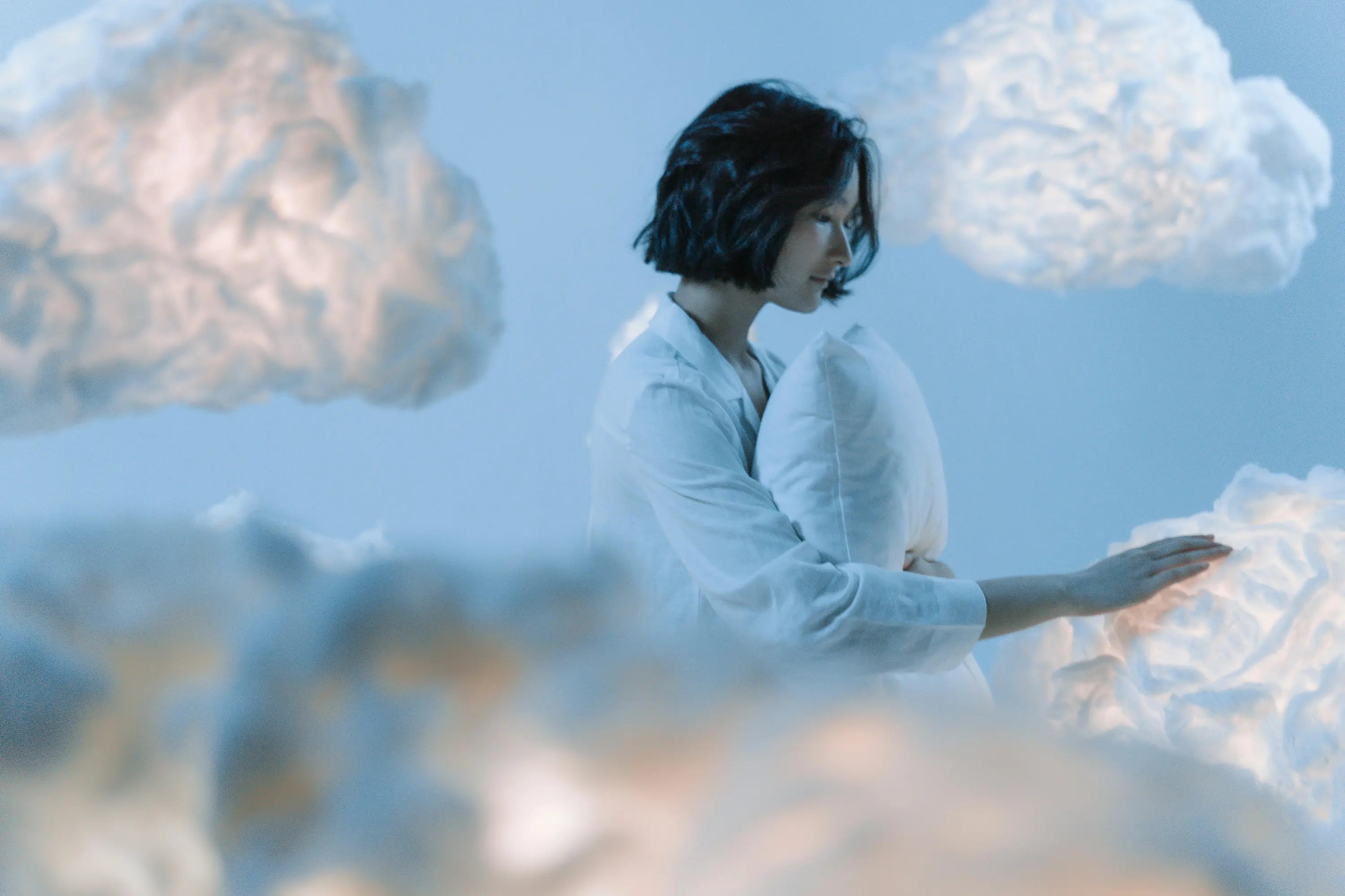 Woman holding a pillow in the clouds, dreaming and getting great sleep.